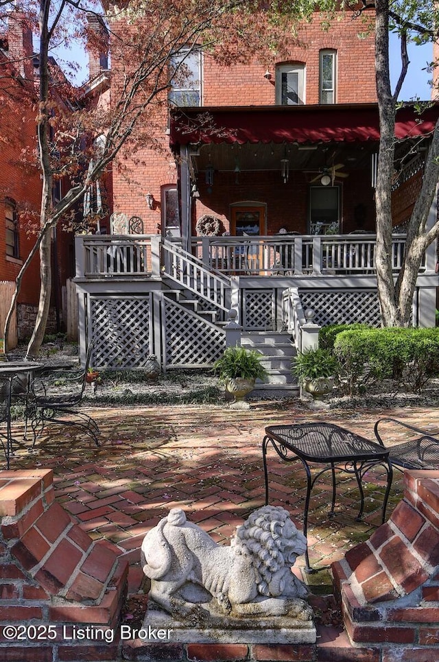 rear view of house featuring brick siding, a patio, and stairs