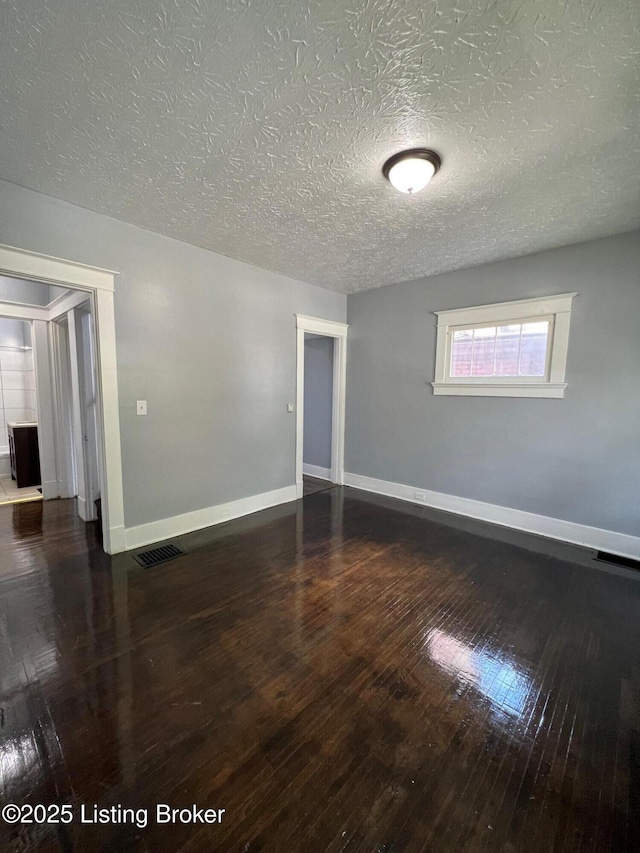 empty room with visible vents, baseboards, hardwood / wood-style floors, and a textured ceiling