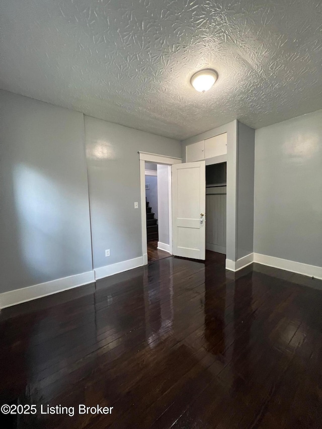 unfurnished bedroom featuring hardwood / wood-style flooring, baseboards, and a textured ceiling