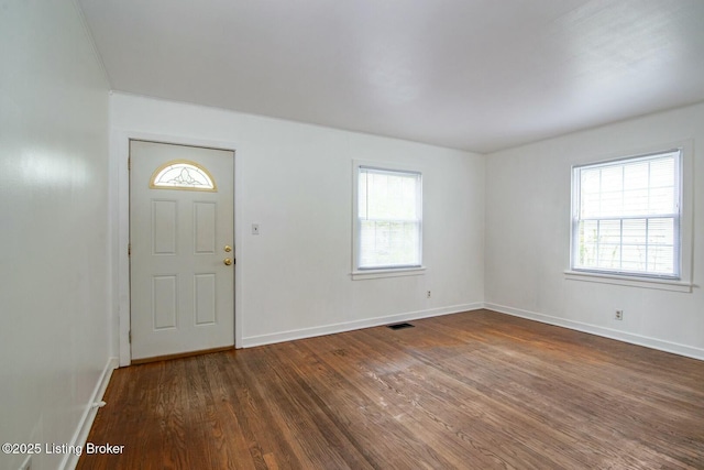foyer featuring dark wood-type flooring, visible vents, and baseboards