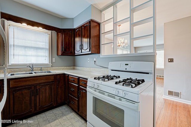 3014 Nadina Dr, Louisville, KY 40220 - kitchen featuring dark brown cabinetry, white gas stove, light countertops, visible vents, and a sink