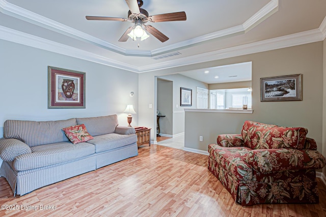 living room with crown molding, ceiling fan, a tray ceiling, visible vents, and wood finished floors