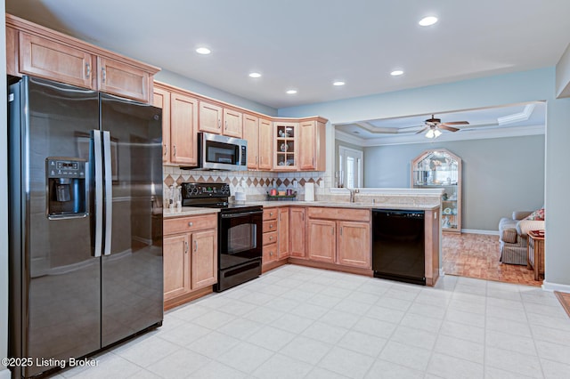 kitchen featuring tasteful backsplash, a peninsula, black appliances, a sink, and light countertops