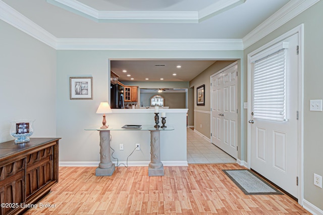 entryway featuring ceiling fan, light wood-type flooring, crown molding, and a raised ceiling