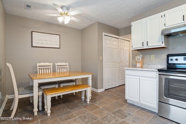kitchen with baseboards, white cabinetry, a ceiling fan, under cabinet range hood, and electric stove