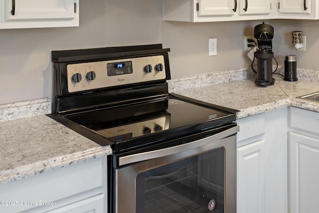 kitchen with stainless steel range with electric stovetop and white cabinetry