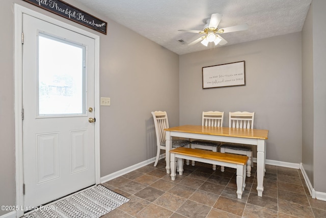 dining space featuring baseboards, ceiling fan, and a textured ceiling