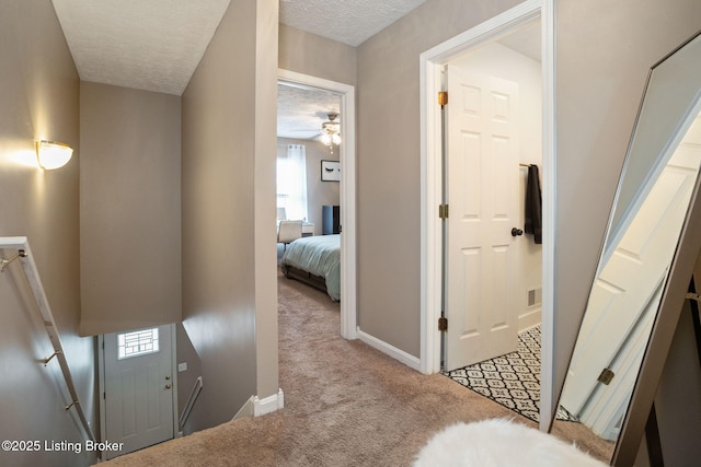corridor featuring a textured ceiling, baseboards, and carpet floors