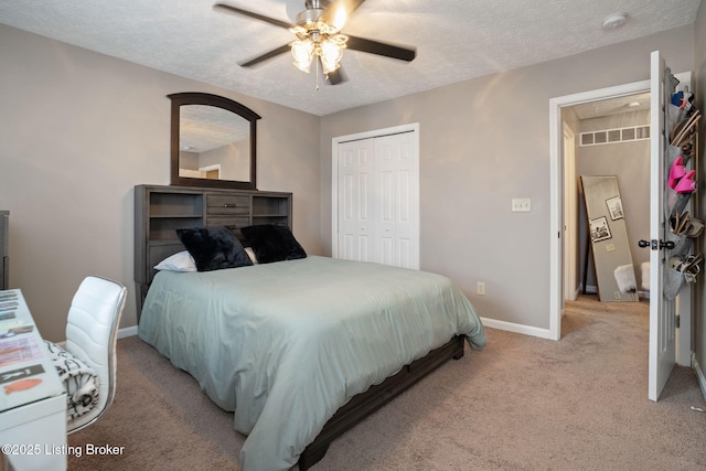 bedroom featuring a closet, baseboards, a textured ceiling, a ceiling fan, and light colored carpet
