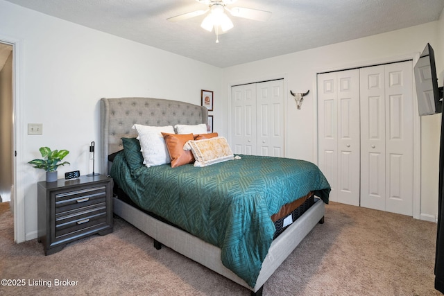 bedroom with two closets, ceiling fan, baseboards, and carpet floors