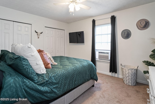 bedroom with baseboards, cooling unit, two closets, a ceiling fan, and carpet floors