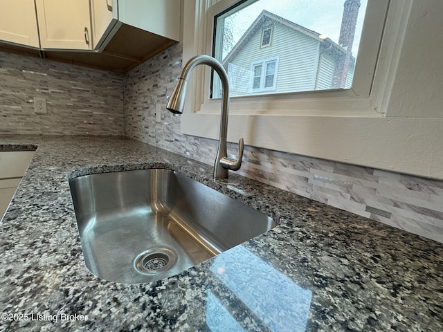 details with dark stone counters, decorative backsplash, and a sink