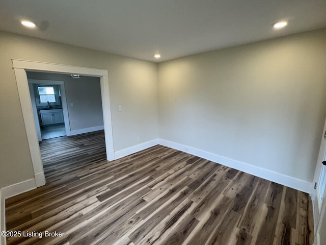 empty room with recessed lighting, dark wood-style flooring, and baseboards