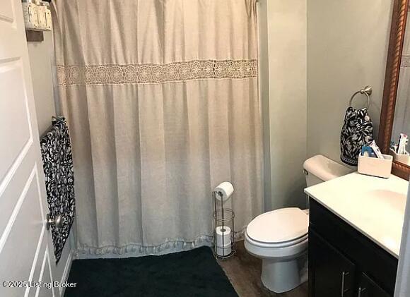 bathroom with toilet, curtained shower, and vanity