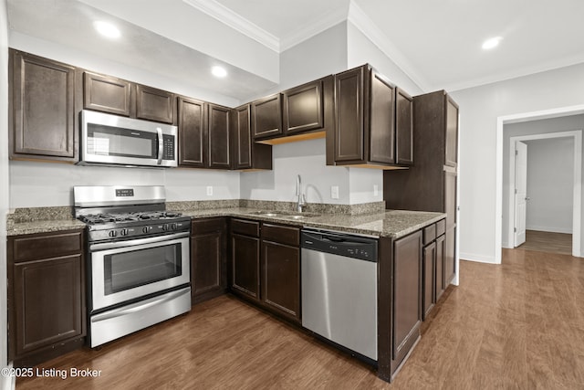 kitchen with dark brown cabinetry, dark wood-style flooring, crown molding, stainless steel appliances, and a sink