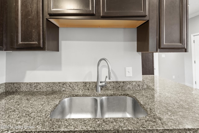 kitchen with a sink, dark brown cabinets, and dark stone countertops