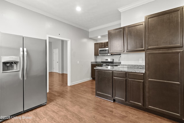 kitchen featuring dark brown cabinetry, light wood-type flooring, ornamental molding, appliances with stainless steel finishes, and baseboards