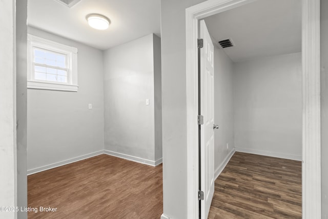 corridor with visible vents, baseboards, and wood finished floors