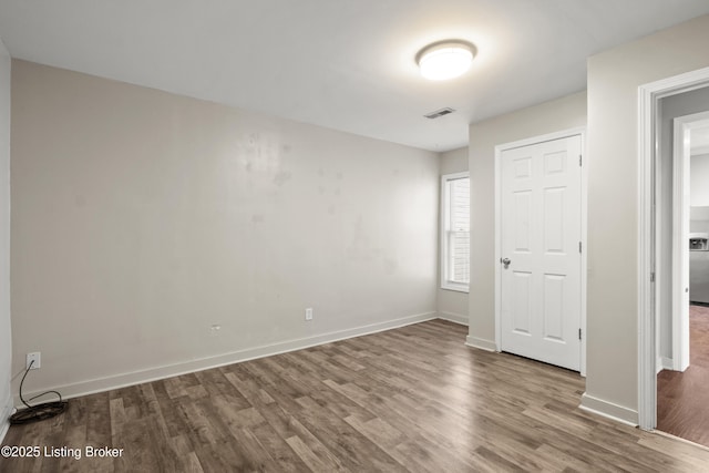 spare room featuring wood finished floors, baseboards, and visible vents