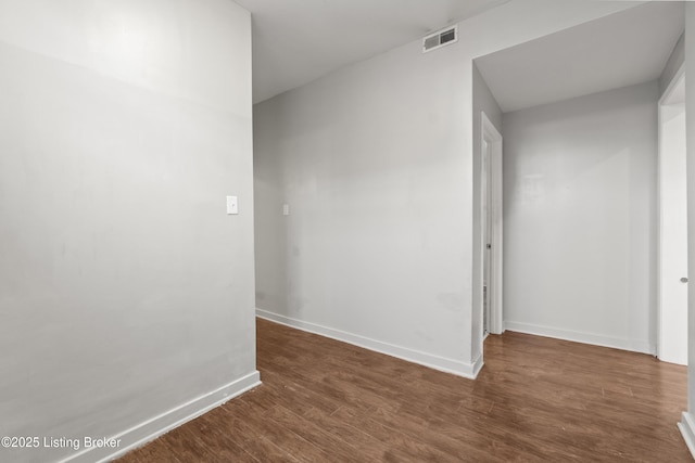 empty room featuring visible vents, baseboards, and dark wood-style floors