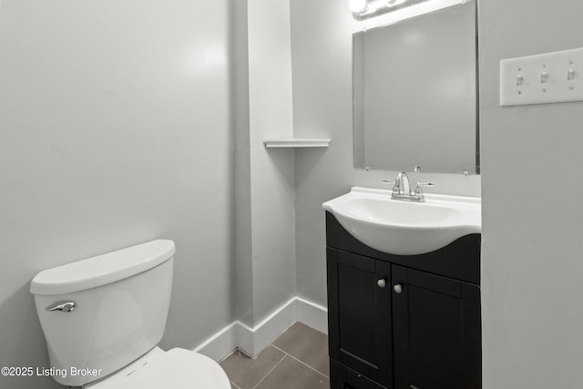 half bathroom with tile patterned floors, toilet, vanity, and baseboards