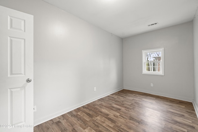spare room featuring wood finished floors, baseboards, and visible vents