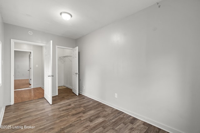 unfurnished bedroom with wood finished floors, a closet, and baseboards