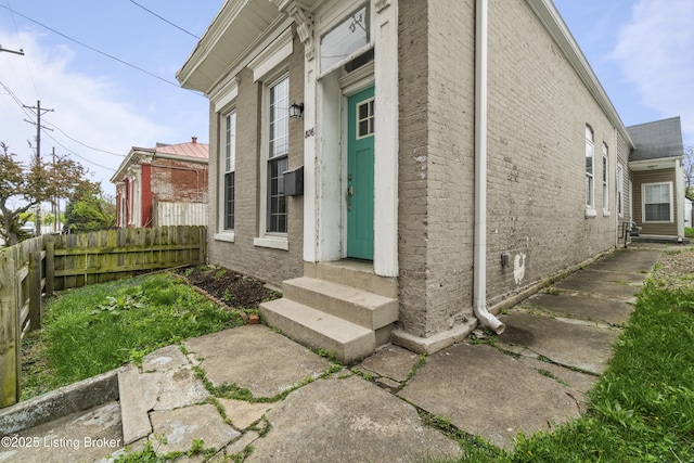 view of home's exterior with entry steps, fence, and brick siding