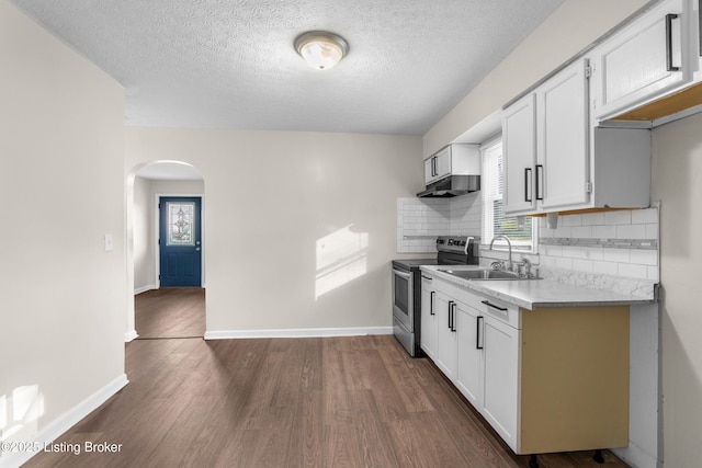 kitchen with dark wood-style floors, arched walkways, a sink, stainless steel range with electric cooktop, and under cabinet range hood