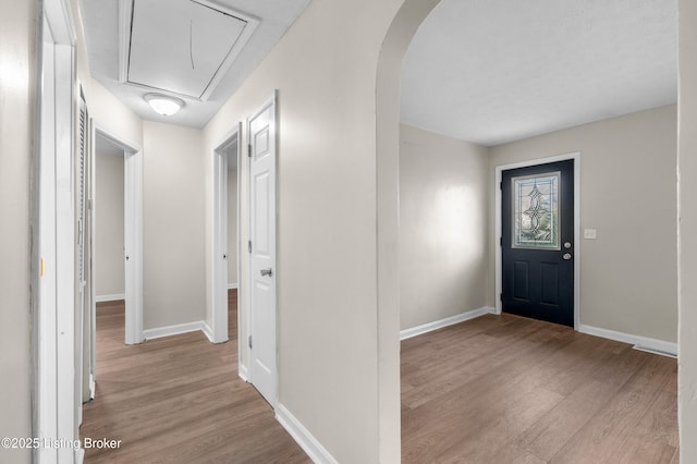 entryway featuring arched walkways, wood finished floors, visible vents, and baseboards