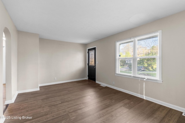 interior space featuring baseboards, wood finished floors, and arched walkways