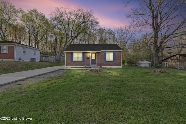 bungalow-style house featuring central AC unit, fence, brick siding, entry steps, and a lawn