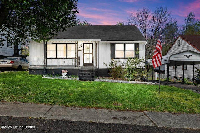 view of front of property with a porch, a shingled roof, and a front lawn