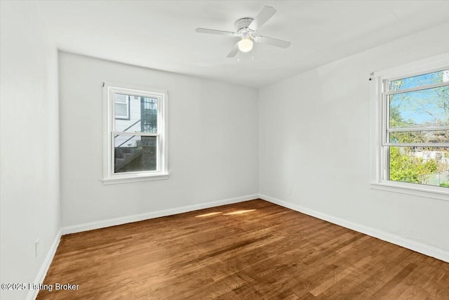 spare room with wood finished floors, baseboards, and a ceiling fan