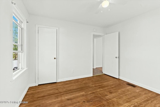 unfurnished bedroom with wood finished floors, ceiling fan, baseboards, and visible vents