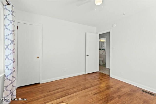 unfurnished bedroom with wood finished floors, ceiling fan, baseboards, and visible vents
