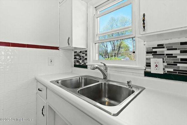 kitchen with light countertops, white cabinetry, and a sink
