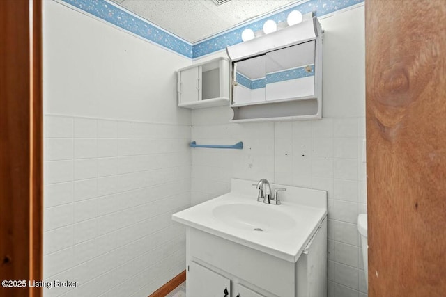 bathroom featuring toilet, tile walls, and vanity