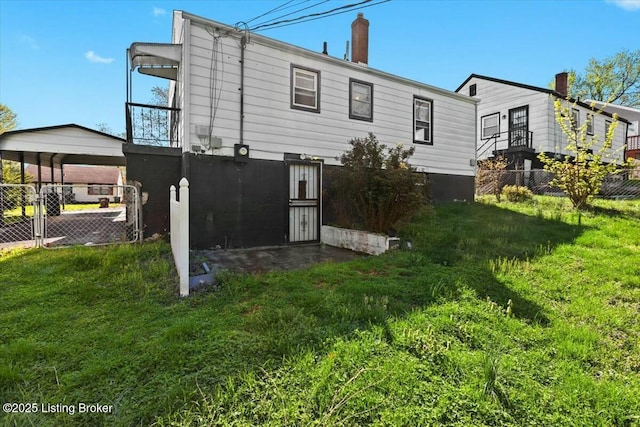 back of property with a detached carport, fence, and a lawn