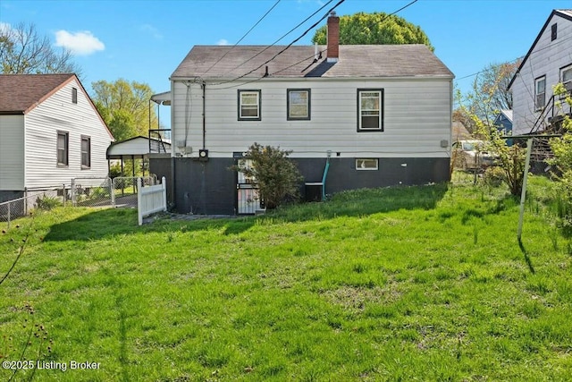 rear view of property with a chimney, fence, and a lawn