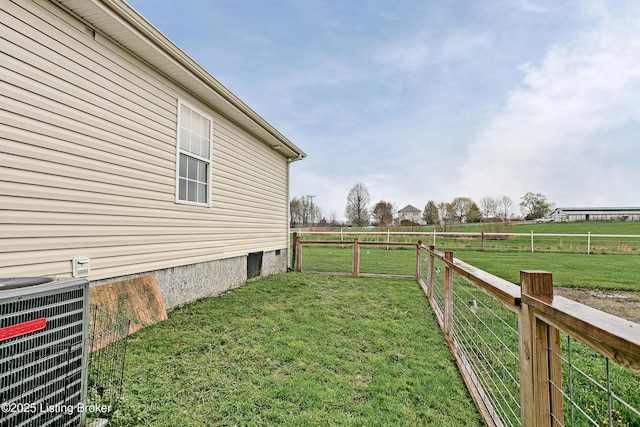 view of yard featuring a rural view, fence, and central AC