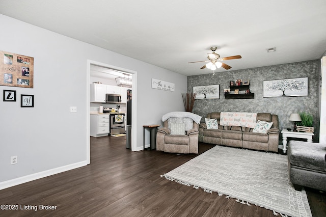 living area with visible vents, an accent wall, ceiling fan, and baseboards