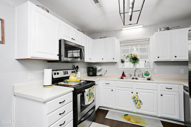 kitchen with light countertops, appliances with stainless steel finishes, a sink, and white cabinetry