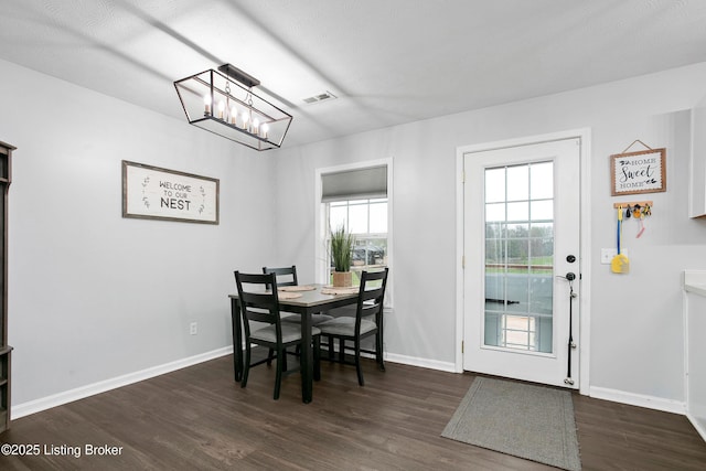 dining space with visible vents, a notable chandelier, dark wood-style floors, and baseboards