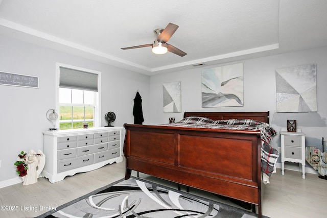 bedroom featuring visible vents, a raised ceiling, and wood finished floors
