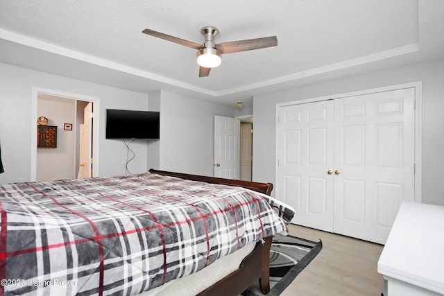 bedroom featuring light wood-type flooring, a closet, and a ceiling fan