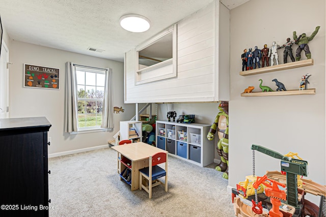 recreation room featuring a textured ceiling, carpet floors, visible vents, and baseboards
