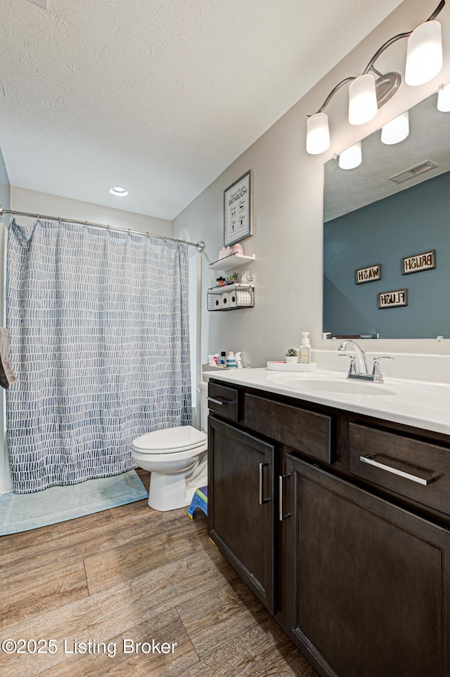 bathroom featuring curtained shower, wood finished floors, visible vents, toilet, and vanity