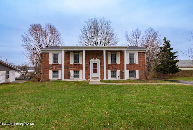 raised ranch with brick siding, a front lawn, and a porch