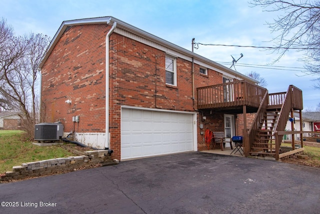 exterior space with a garage, aphalt driveway, cooling unit, stairs, and brick siding